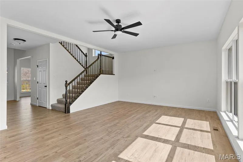 Unfurnished living room featuring light wood-type flooring, stairway, and a ceiling fan — 563 Edison Way, Wentzville, MO 63385