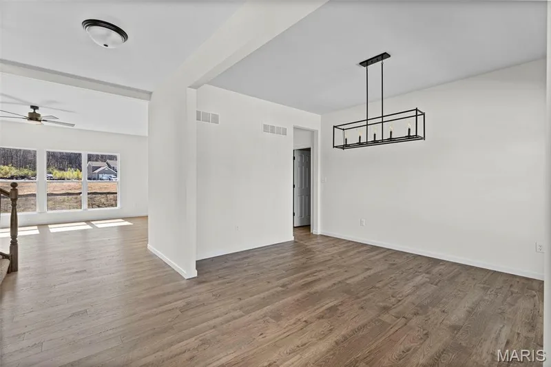 Unfurnished dining area with wood finished floors, a chandelier, and a ceiling fan — 563 Edison Way, Wentzville, MO 63385