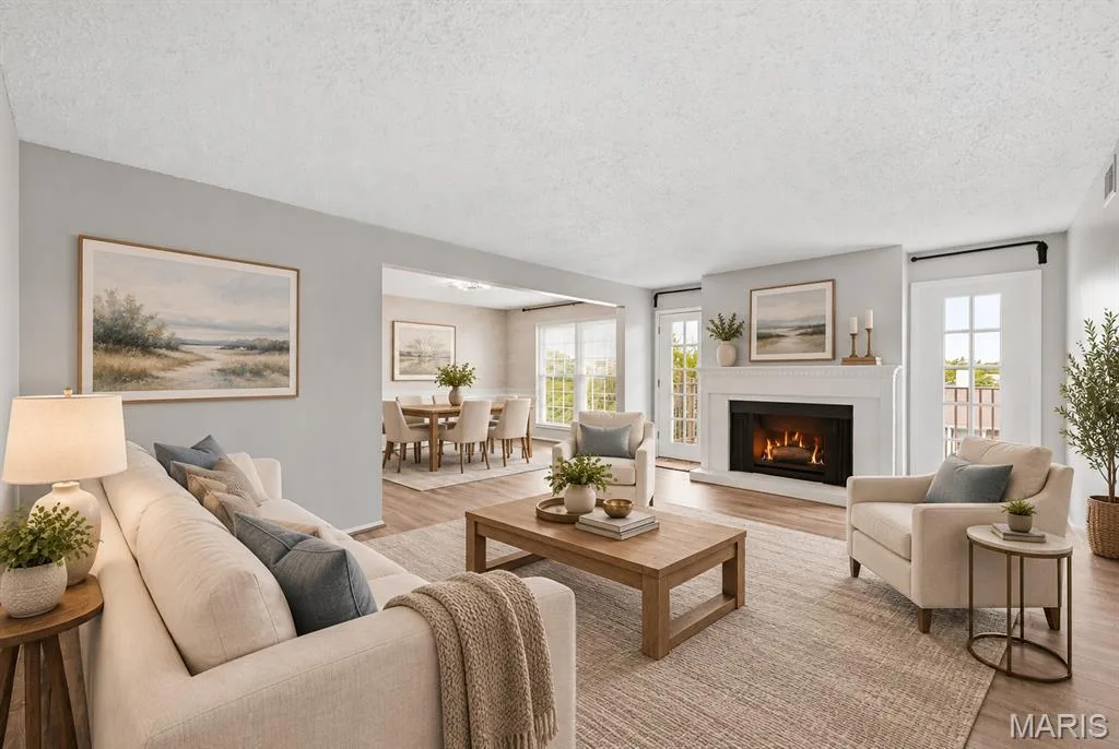 Fireplace with a white mantel, wood-finish flooring, and white French doors — 14443 Bantry Lane #16, Chesterfield, MO 63017