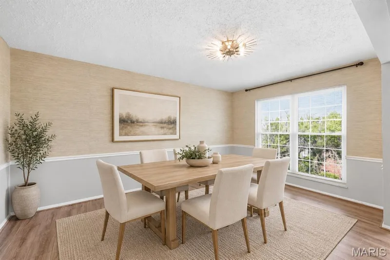 Wood-finish flooring, accent wall with wainscoting, and a modern ceiling light fixture — 14443 Bantry Lane #16, Chesterfield, MO 63017