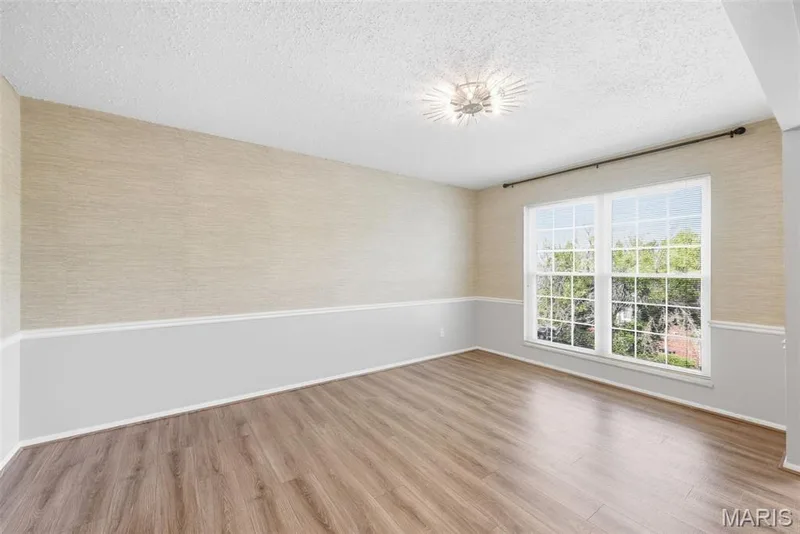Wood-finish flooring, two-tone wall treatment, crown molding, and a decorative ceiling light fixture — 14443 Bantry Lane #16, Chesterfield, MO 63017