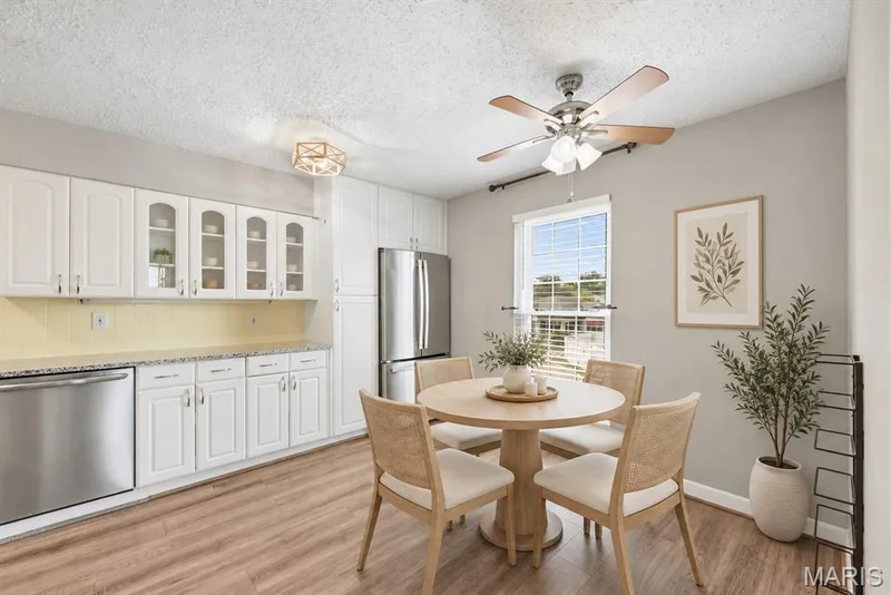 White cabinetry with glass-front accents, stainless steel appliances, wood-finish flooring, a ceiling fan, and a double-pane window — 14443 Bantry Lane #16, Chesterfield, MO 63017
