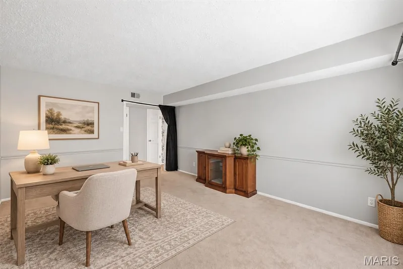 Wall-to-wall carpeting and neutral wall tones define this versatile space, featuring a chair rail and a white paneled door — 14443 Bantry Lane #16, Chesterfield, MO 63017