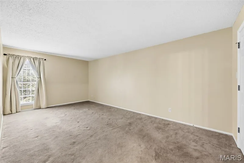 Carpeted room featuring a window with blinds and drapes, light-toned walls, and a white ceiling — 14443 Bantry Lane #16, Chesterfield, MO 63017