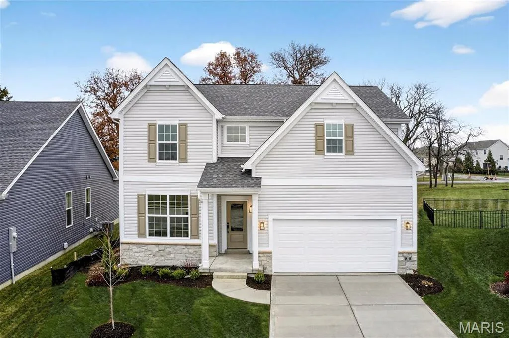 Traditional-style house with stone siding, a shingled roof, concrete driveway, and an attached garage — 210 Randlin Drive, O'Fallon, MO 63367