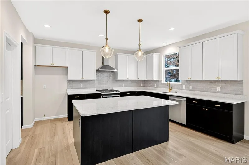 Kitchen with dark cabinets, decorative light fixtures, white cabinets, stainless steel appliances, and a center island — 210 Randlin Drive, O'Fallon, MO 63367