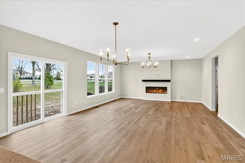 Family room with a lit fireplace, light wood finished floors, a chandelier, and recessed lighting — 210 Randlin Drive, O'Fallon, MO 63367