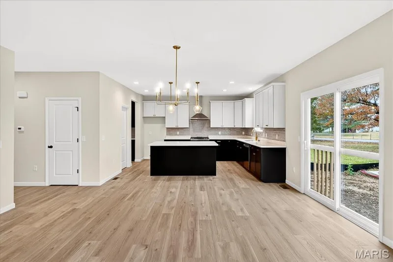 Kitchen featuring breakfast area dark cabinetry, decorative light fixtures, a chandelier, a kitchen island, and light countertops — 210 Randlin Drive, O'Fallon, MO 63367