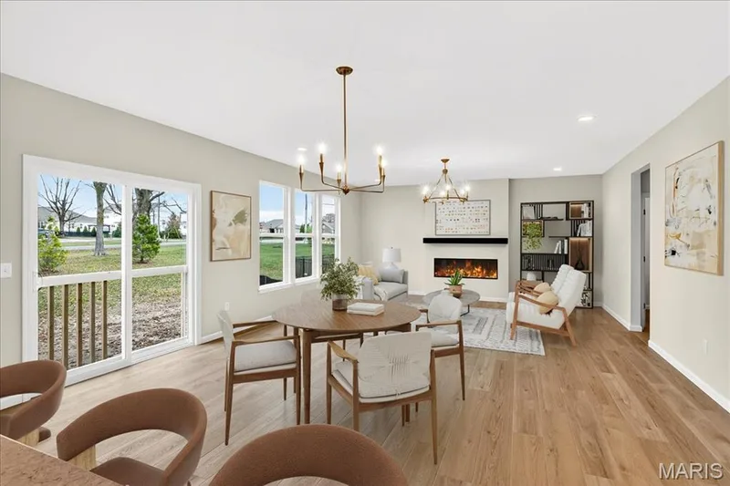 Dining area with a warm lit fireplace, a chandelier, light wood finished floors, and recessed lighting — 210 Randlin Drive, O'Fallon, MO 63367
