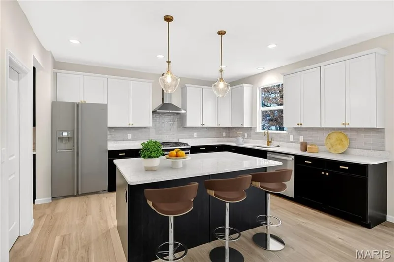 Kitchen with dark cabinetry, appliances with stainless steel finishes, decorative light fixtures, light stone countertops, and recessed lighting — 210 Randlin Drive, O'Fallon, MO 63367