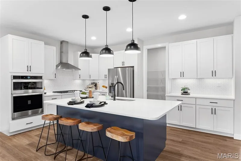 Kitchen featuring decorative backsplash, a kitchen bar, dark wood finished floors, and recessed lighting — 1 TBB Canterbury @ Kreder Farms, St Charles, MO 63304
