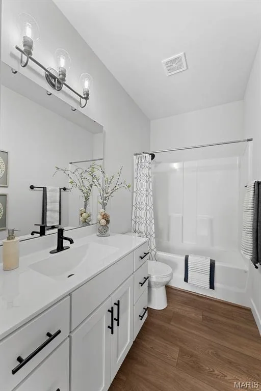Bathroom featuring shower / bath combo, dark wood finished floors, and vanity — 1 TBB Canterbury @ Kreder Farms, St Charles, MO 63304