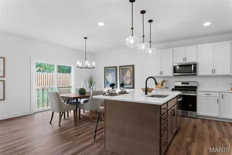 Kitchen featuring white cabinets, appliances with stainless steel finishes, a center island with sink, decorative light fixtures, and recessed lighting — 1 TBB Rochester @ Kreder Farms, St Charles, MO 63304
