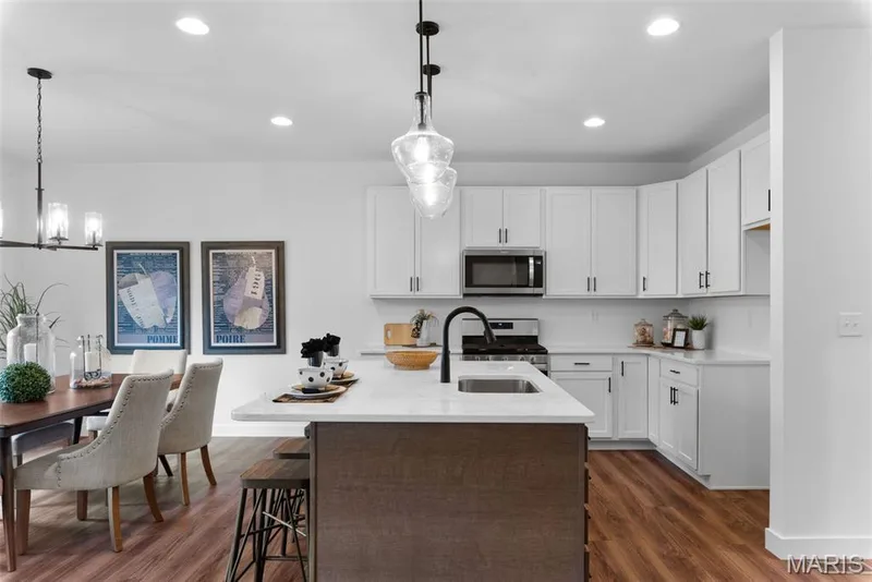 Kitchen with white cabinetry, a center island with sink, dark wood-type flooring, stainless steel appliances, and pendant lighting — 1 TBB Rochester @ Kreder Farms, St Charles, MO 63304