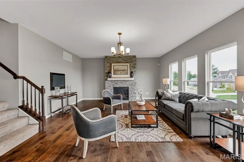 Living area featuring stairs, a chandelier, wood finished floors, and a fireplace — 1 TBB Sienna @ Kreder Farms, St Charles, MO 63304