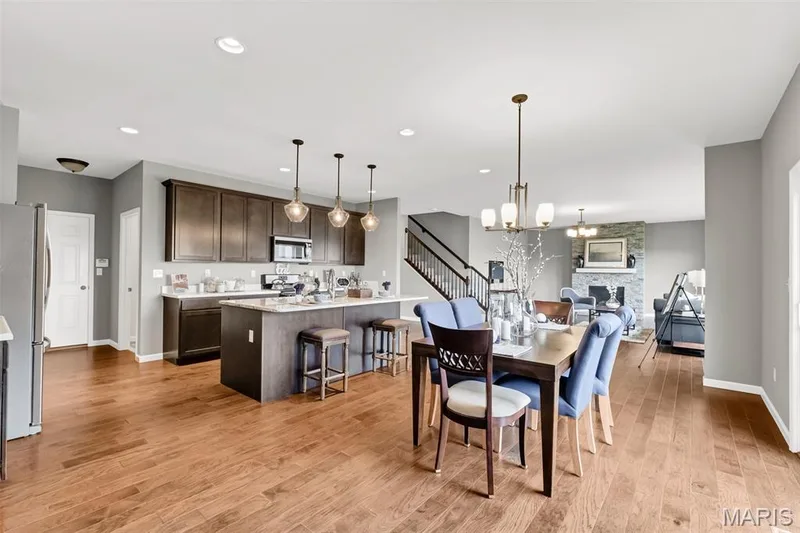 Dining room with light wood-type flooring, a stone fireplace, recessed lighting, a chandelier, and stairway — 1 TBB Sienna @ Kreder Farms, St Charles, MO 63304