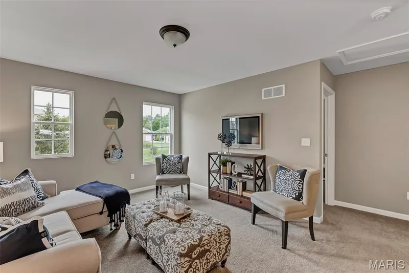 Carpeted living room featuring baseboards and attic access — 1 TBB Sienna @ Kreder Farms, St Charles, MO 63304