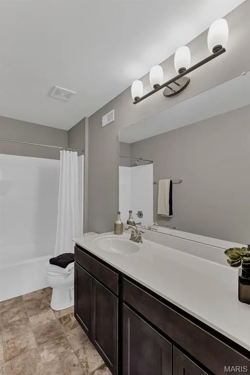 Full bath featuring vanity, shower / bath combination with curtain, and stone finish floors — 1 TBB Sienna @ Kreder Farms, St Charles, MO 63304