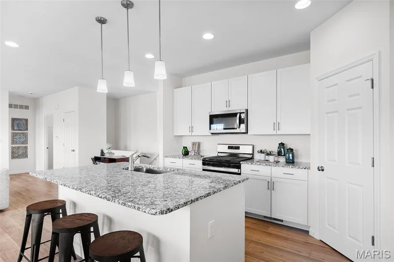 Kitchen featuring a kitchen bar, appliances with stainless steel finishes, recessed lighting, light wood-style flooring, and an island with sink — 1 TBB Westbrook @ Kreder Farms, St Charles, MO 63304