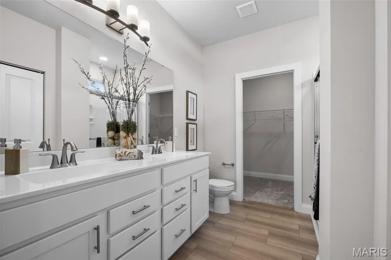 Full bath with a walk in closet, double vanity, and light wood-style floors — 1 TBB Rockport @ Kreder Farms, St Charles, MO 63304