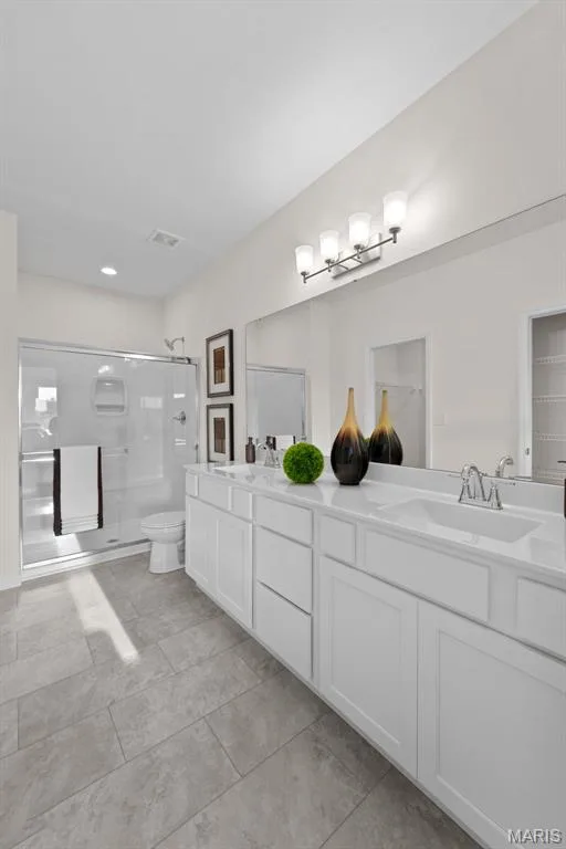 Full bathroom with a shower stall, double vanity, a spacious closet, and light tile patterned floors — 1 TBB Savoy @ Kreder Farms, St Charles, MO 63304