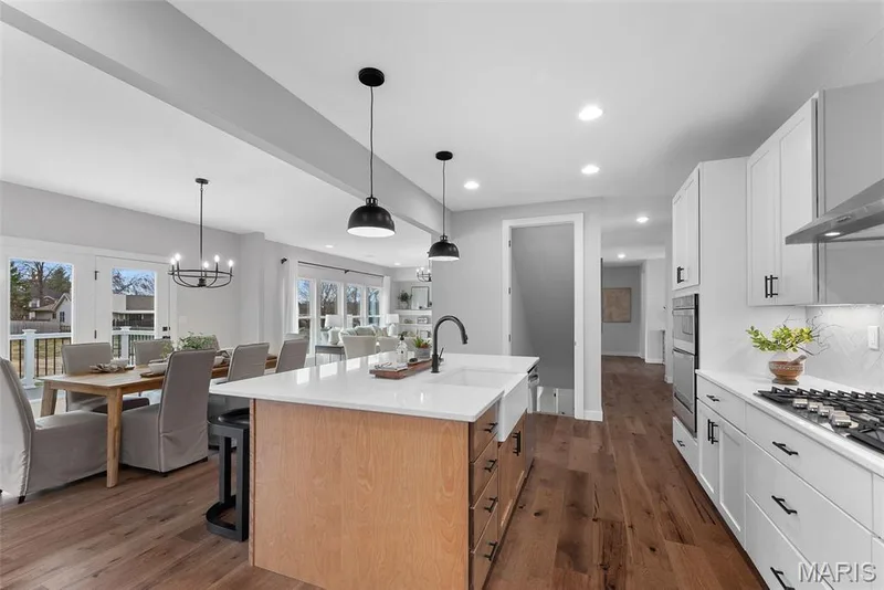 Kitchen with recessed lighting, white cabinets, dark wood finished floors, decorative light fixtures, and a kitchen island with sink — 1 TBB Bridgeport @ Kreder Farms, St Charles, MO 63304