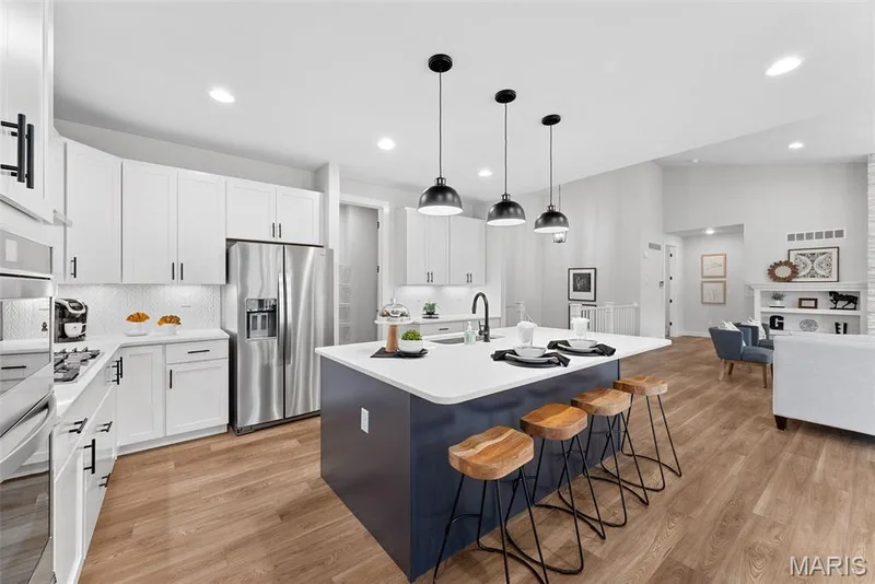 Kitchen with an island with sink, hanging light fixtures, decorative backsplash, white cabinetry, and recessed lighting — Canterbury @ Providence Estates, Foristell, MO 63348