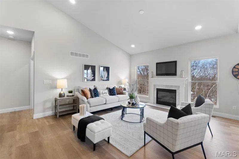 Living room featuring a glass covered fireplace, recessed lighting, light wood finished floors, and high vaulted ceiling — 1 TBB Rockport @ Creekside Sommers, O'Fallon, MO 63367