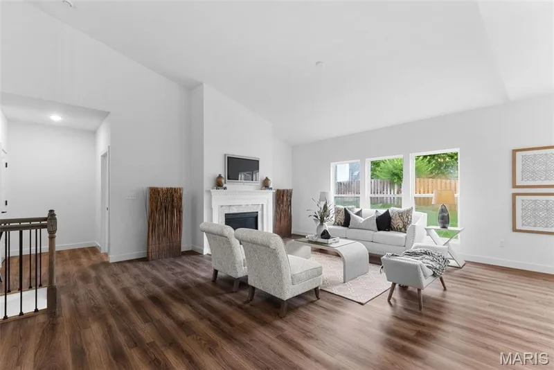 Living area with high vaulted ceiling, dark wood-style flooring, and a glass covered fireplace — 1 TBB Rochester @ Creekside Sommers, O'Fallon, MO 63367