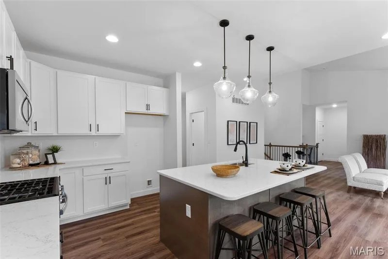 Kitchen with white cabinetry, an island with sink, a kitchen breakfast bar, dark wood-style flooring, and recessed lighting — 1 TBB Rochester @ Creekside Sommers, O'Fallon, MO 63367