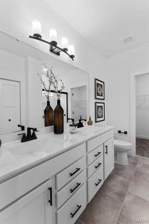 Bathroom featuring a walk in closet, double vanity, and light tile patterned floors — 1 TBB Rochester @ Creekside Sommers, O'Fallon, MO 63367