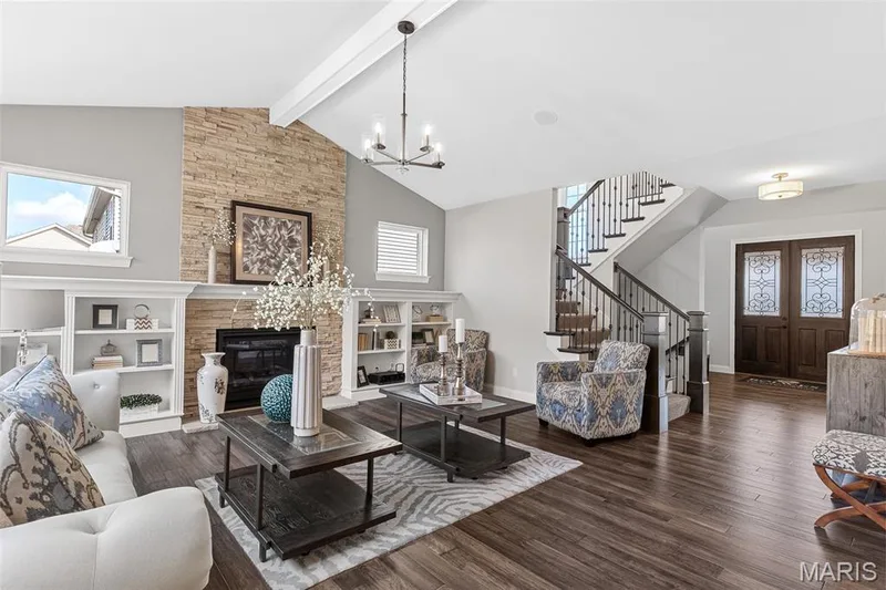 Living room with dark wood-style flooring, beamed ceiling, stairs, high vaulted ceiling, and a chandelier — 1 TBB Kingston @Willow Grove, Dardenne Prairie, MO 63368