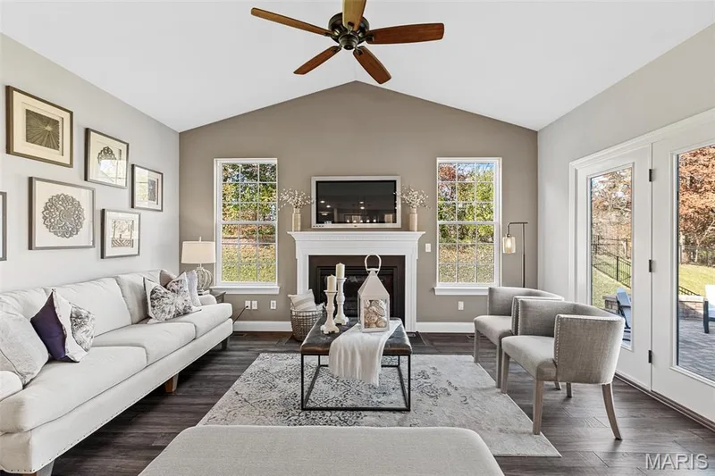 Living room featuring lofted ceiling, dark wood-type flooring, a fireplace, and a ceiling fan — 1 TBB Kingston @Willow Grove, Dardenne Prairie, MO 63368