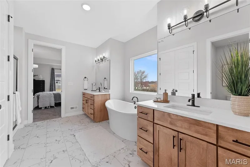 Ensuite bathroom with two vanities, a freestanding bath, light marble finish floors, and recessed lighting — 1 TBB Bridgeport @ Chateau De Fond Du Lac, Lake St. Louis, MO 63367