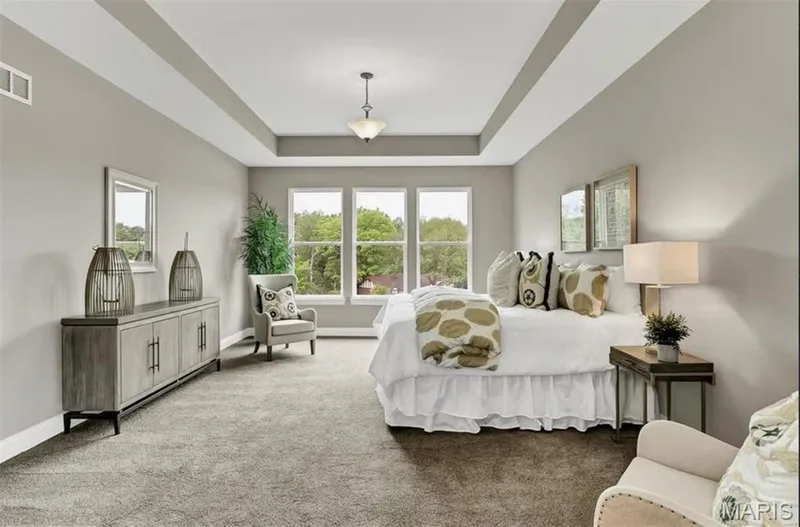 Bedroom with light carpet, a tray ceiling, and multiple windows — 1 TBB Monaco @ Chateau De Fond Du Lac, Lake St. Louis, MO 63367