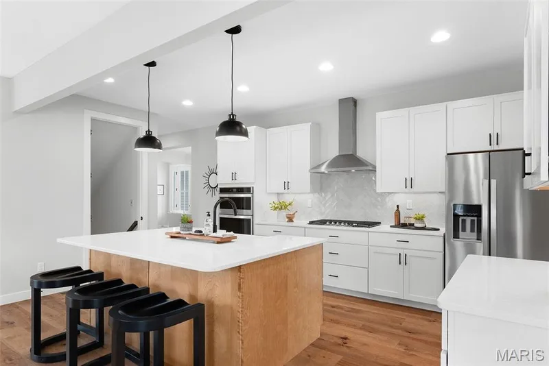 Kitchen with decorative backsplash, light wood-style flooring, an island with sink, white cabinetry, and recessed lighting — 1 TBB Bridgeport @Willow Grove, Dardenne Prairie, MO 63368