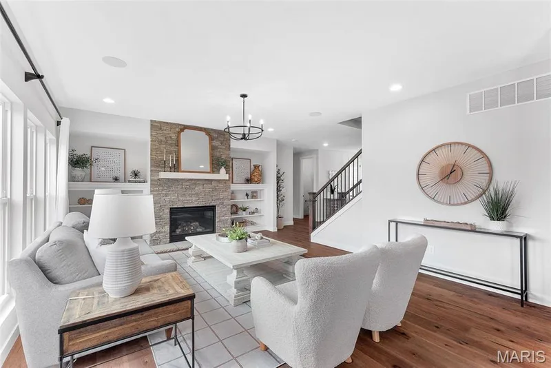 Living room with a stone fireplace, wood finished floors, stairs, a chandelier, and recessed lighting — 1 TBB Bridgeport @Willow Grove, Dardenne Prairie, MO 63368