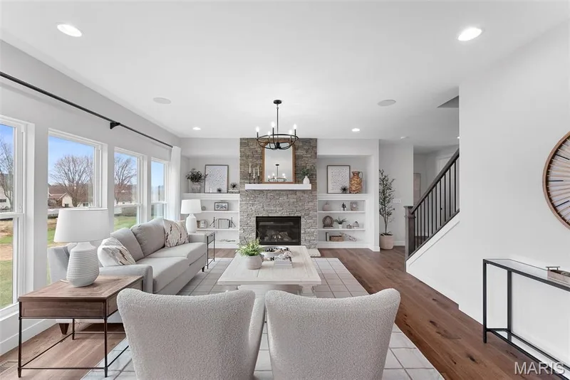 Living room featuring recessed lighting, a fireplace, a chandelier, wood finished floors, and stairs — 1 TBB Bridgeport @Willow Grove, Dardenne Prairie, MO 63368
