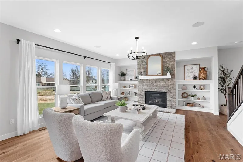 Living area featuring a fireplace, a chandelier, recessed lighting, light wood-style floors, and stairs — 1 TBB Bridgeport @Willow Grove, Dardenne Prairie, MO 63368