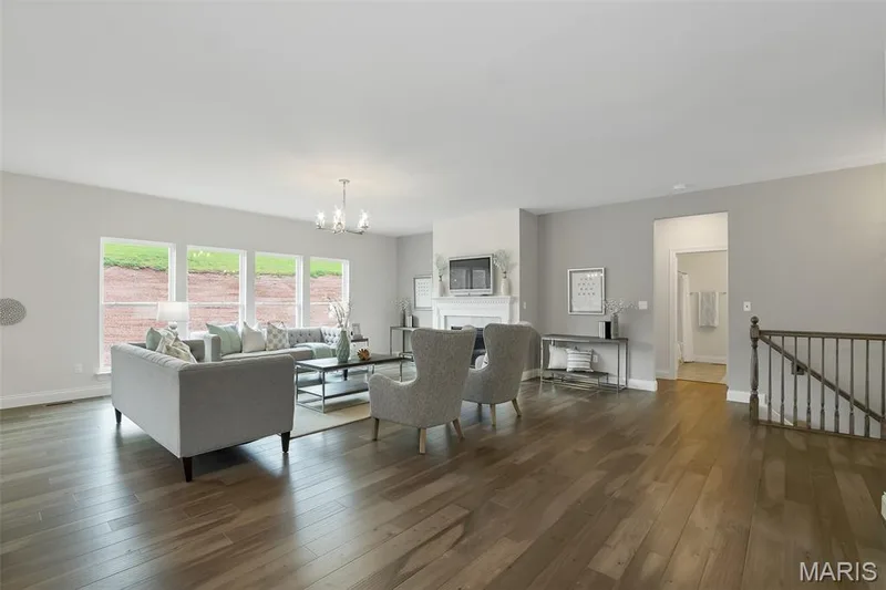 Living room featuring a chandelier, wood finished floors, and a fireplace — 1 TBB Waverly @ Chateau De Fond Du Lac, Lake St. Louis, MO 63367