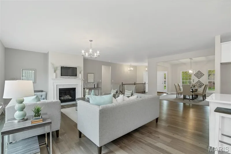 Living room featuring light wood finished floors, a glass covered fireplace, and a chandelier — 1 TBB Waverly @ Chateau De Fond Du Lac, Lake St. Louis, MO 63367