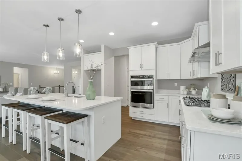 Kitchen featuring a kitchen bar, light stone counters, light wood finished floors, white cabinets, and recessed lighting — 1 TBB Waverly @ Chateau De Fond Du Lac, Lake St. Louis, MO 63367