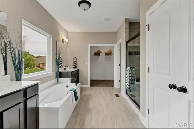Full bathroom featuring two vanities, a walk in closet, a garden tub, and a shower stall — 1 TBB Monaco @Willow Grove, Dardenne Prairie, MO 63368