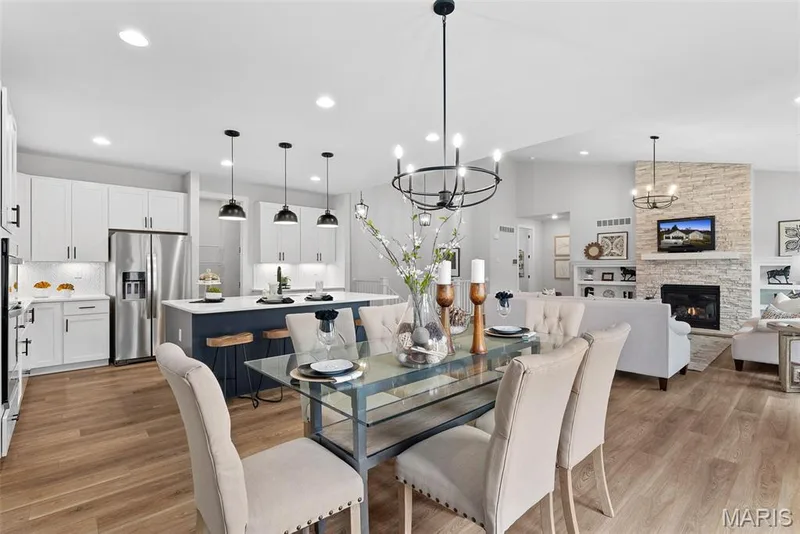 Dining area featuring light wood-type flooring, a stone fireplace, recessed lighting, lofted ceiling, and a chandelier — 1 TBB Canterbury@ Willow Grove, Dardenne Prairie, MO 63368