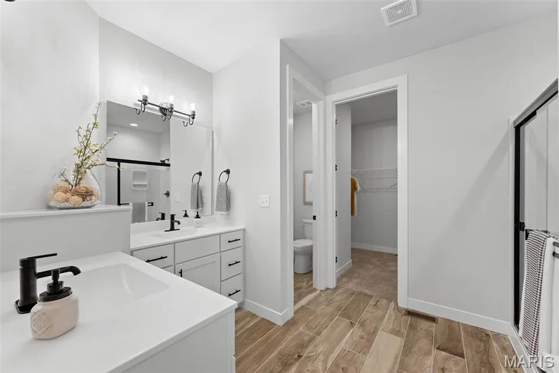 Full bathroom featuring a stall shower, wood finish floors, vanity, and a walk in closet — 1 TBB Canterbury@ Willow Grove, Dardenne Prairie, MO 63368