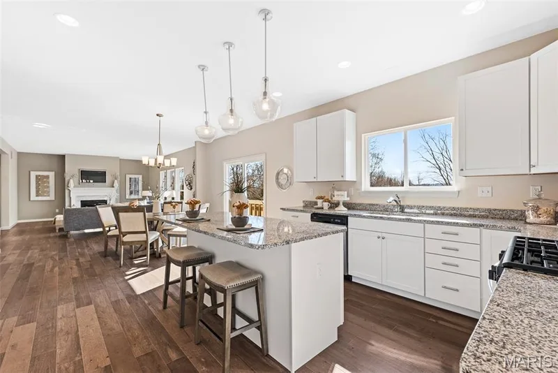 Kitchen featuring a kitchen bar, a center island, white cabinets, dark wood-style floors, and light stone countertops — 1 TBB Princeton @ Creekside Sommers, O'Fallon, MO 63367