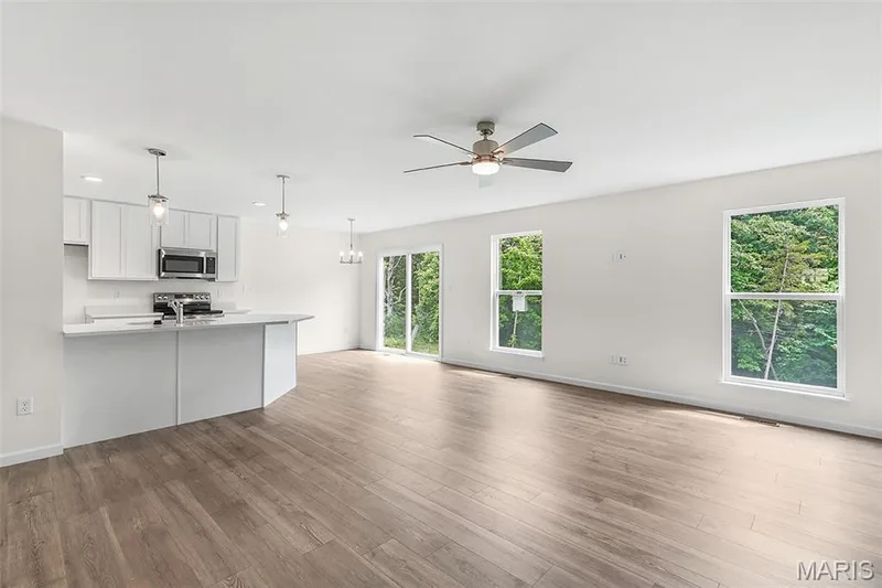 Unfurnished living room with a chandelier, light wood finished floors, and ceiling fan — 15 Integrity Court, O'Fallon, MO 63385