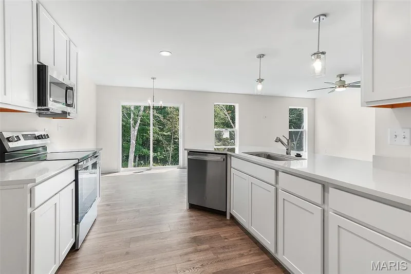 Kitchen with stainless steel appliances, white cabinets, hanging light fixtures, light wood-style flooring, and recessed lighting — 15 Integrity Court, O'Fallon, MO 63385