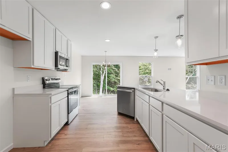 Kitchen featuring appliances with stainless steel finishes, hanging light fixtures, white cabinets, a peninsula, and recessed lighting — 15 Integrity Court, O'Fallon, MO 63385