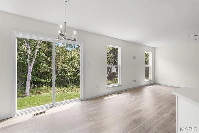 Unfurnished dining area featuring a chandelier and light wood-style flooring — 15 Integrity Court, O'Fallon, MO 63385